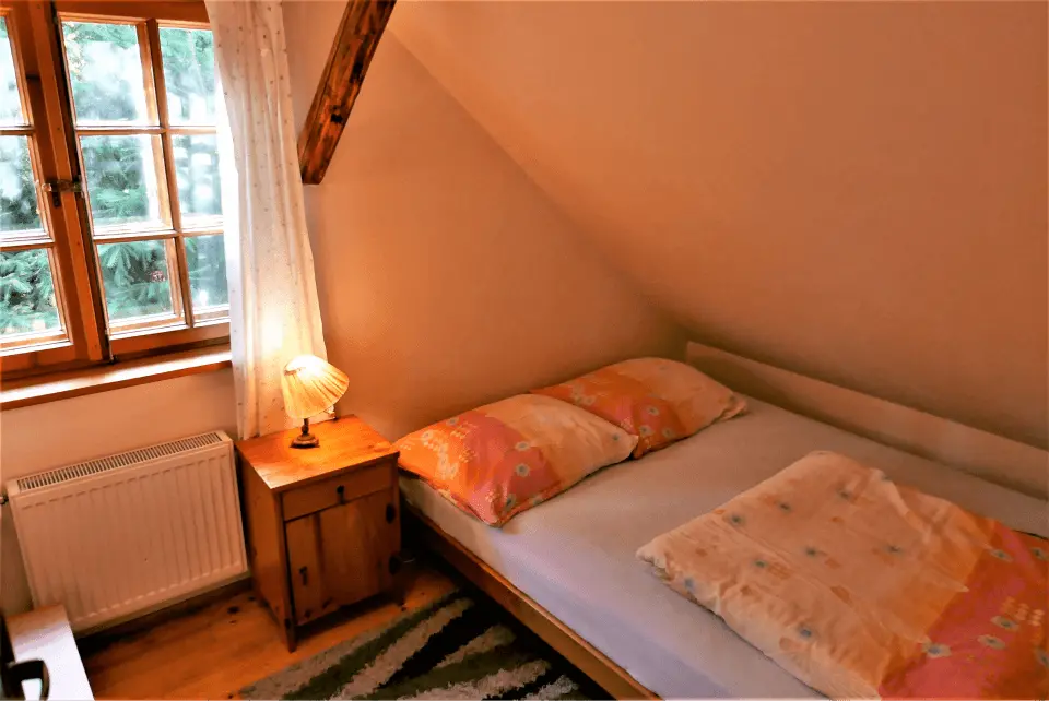 Sypialnia z oknem, łóżkiem oraz lampką nocną