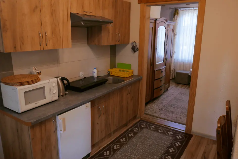 Kuchnia z mikrofalówką, czajnikiem oraz lodówką i innymi potrzebnymi rzeczami do codziennego gotowania