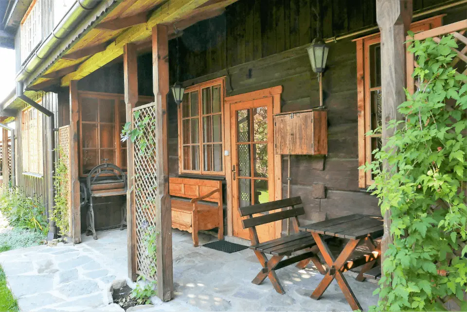 Apartament pod modrzewiem ze strony ogrodu, przy wejściu widzimy stół z ławkami